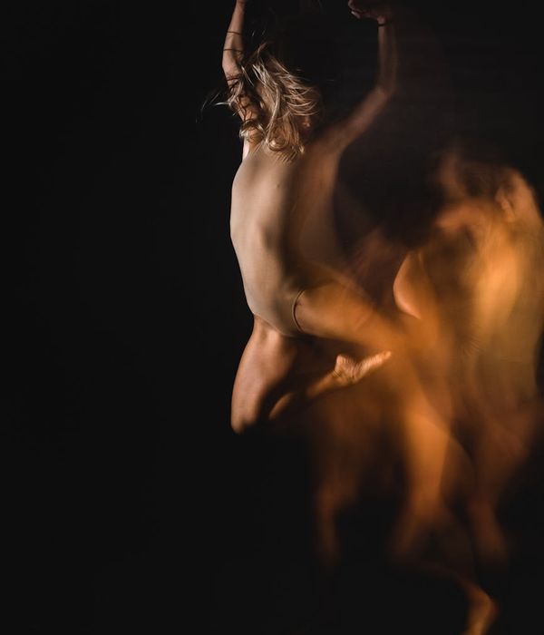 Woman performing a fluid cardio movement in a dark studio.